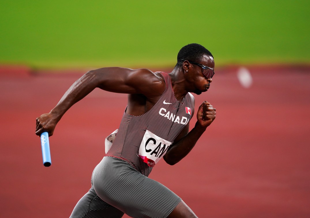 Aaron Brown runs with a baton in his hand 