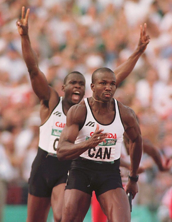 Bruny Surin raises his arms in celebration after passing the baton to Donovan Bailey