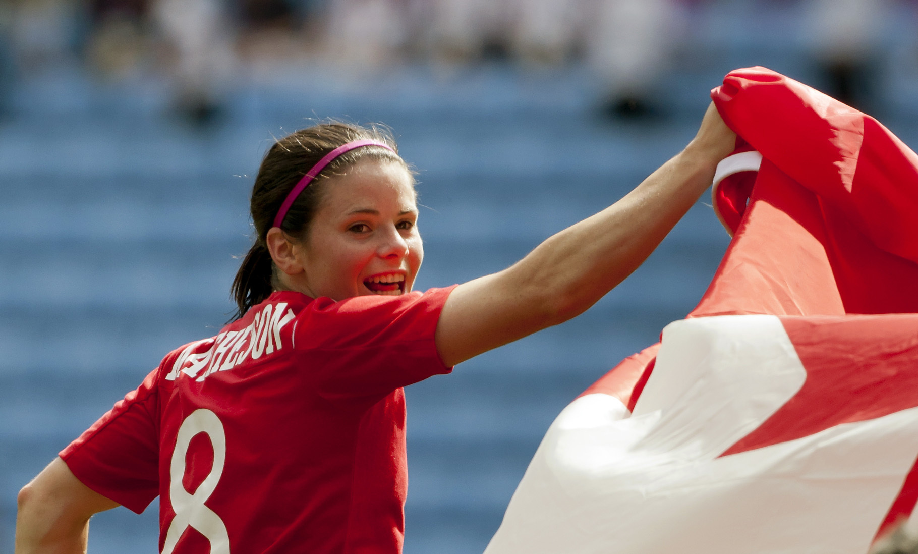 Diana Matheson looks over her shoulder while waving the Canadian flag 