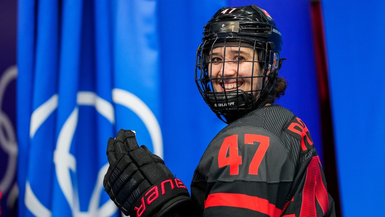 Jamie Lee Rattray smiles through her face shield as she walks off the ice