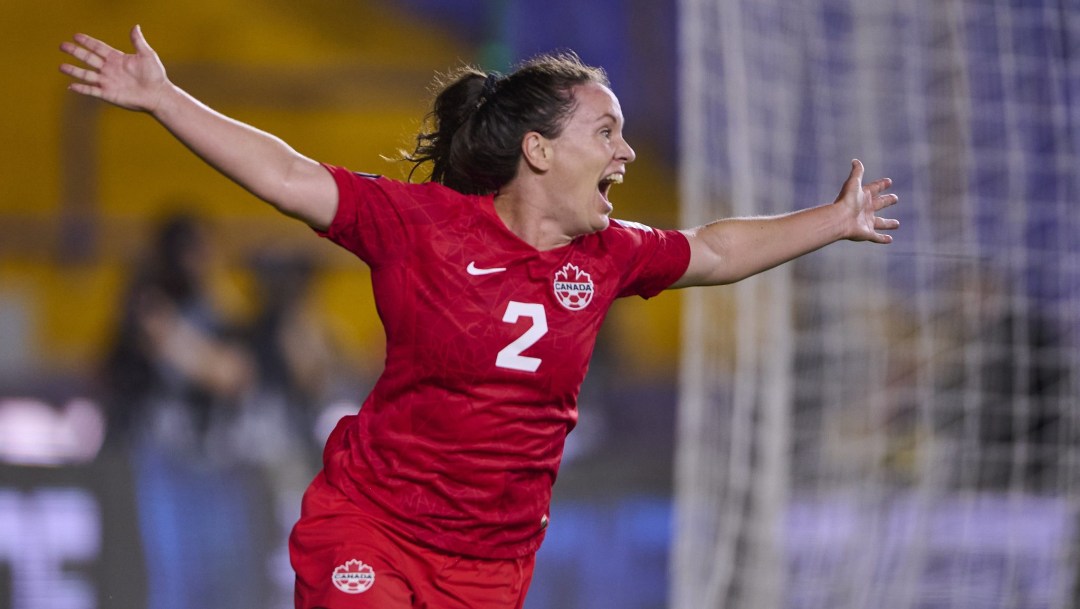 Allysha Chapman holds her arms wide with a big grin in celebration of scoring a goal