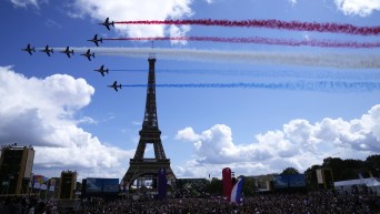 Fighter jets leave five trails of colour as they fly past the Eiffel Tower