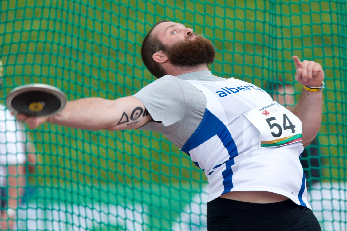 Ryan Sommer leans back as he throws a discus