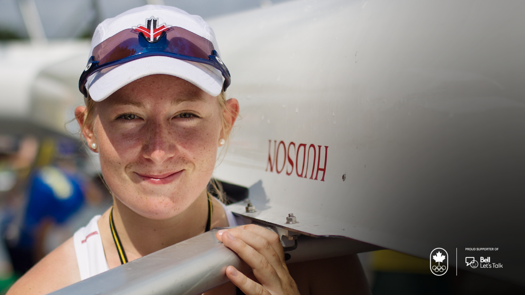 Caileigh Filmer carries a rowing shell on her shoulder while looking straight at camera