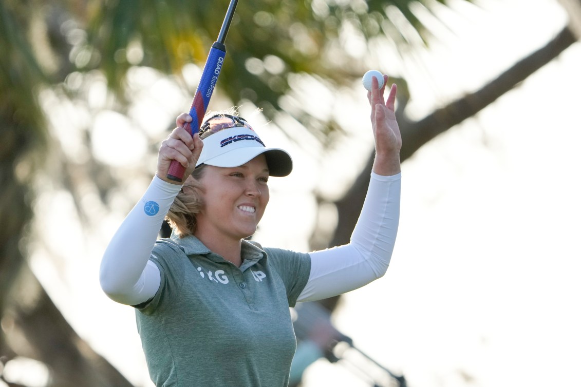 Brooke Henderson raises her arms in celebration after a final putt