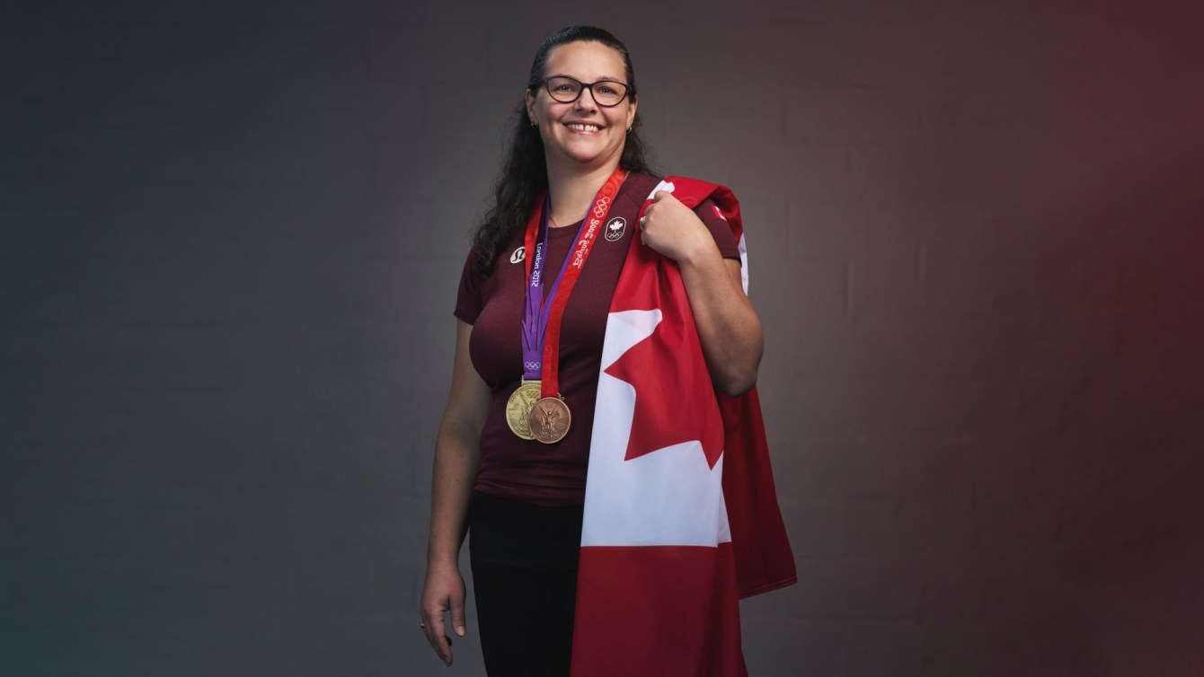 Christine Girard poses with the Canadian flag over one shoulder as she wears her Olympic medals