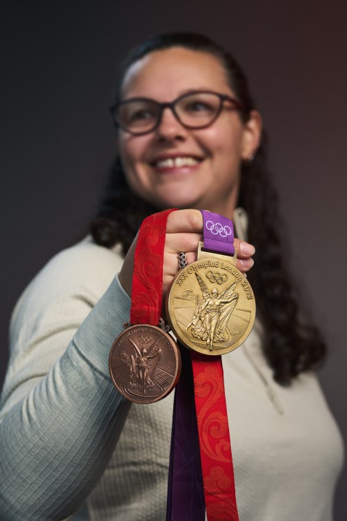 Christine Girard holds her Olympic gold and bronze medals up in front of herself