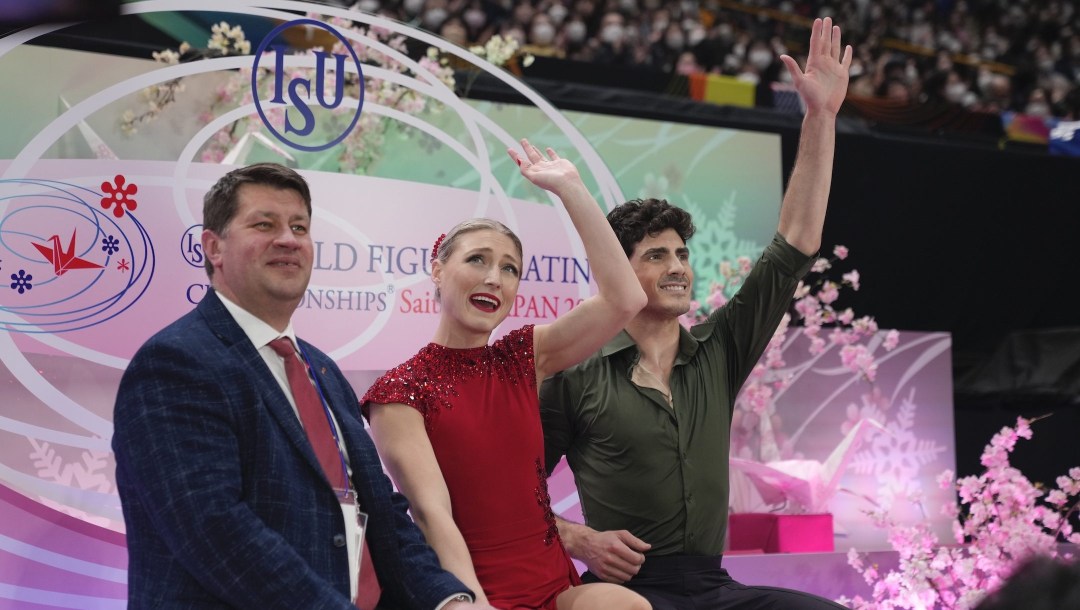 Piper Gilles, center, and Paul Poirier, right, of Canada react to audience members after getting their score for their performance in the ice dance free dance program in the World Figure Skating Championships in Saitama, north of Tokyo, Saturday, March 25, 2023. (AP Photo/Hiro Komae)