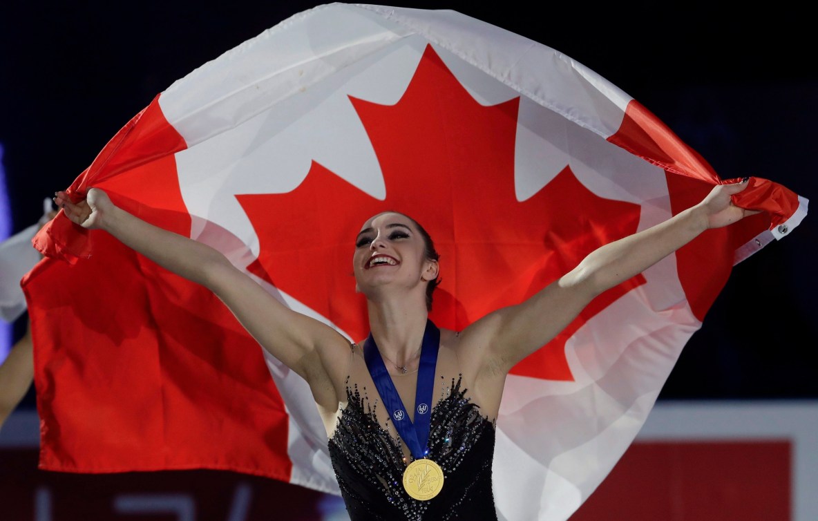 Kaetlyn Osmond holds a Canadian flag behind her while wearing her gold medal