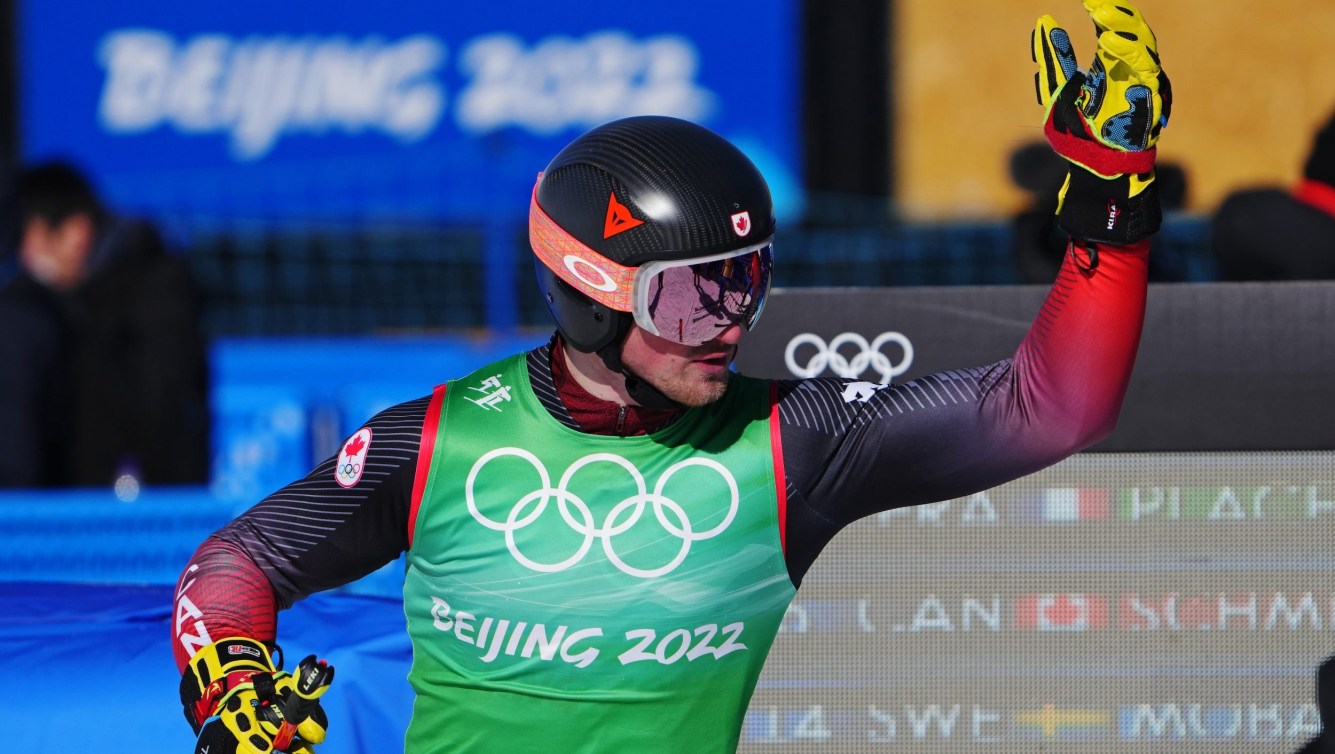 Reece Howden raises his arm in the finish area of a ski cross race