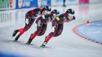 Three speed skaters go around a corner in perfect line