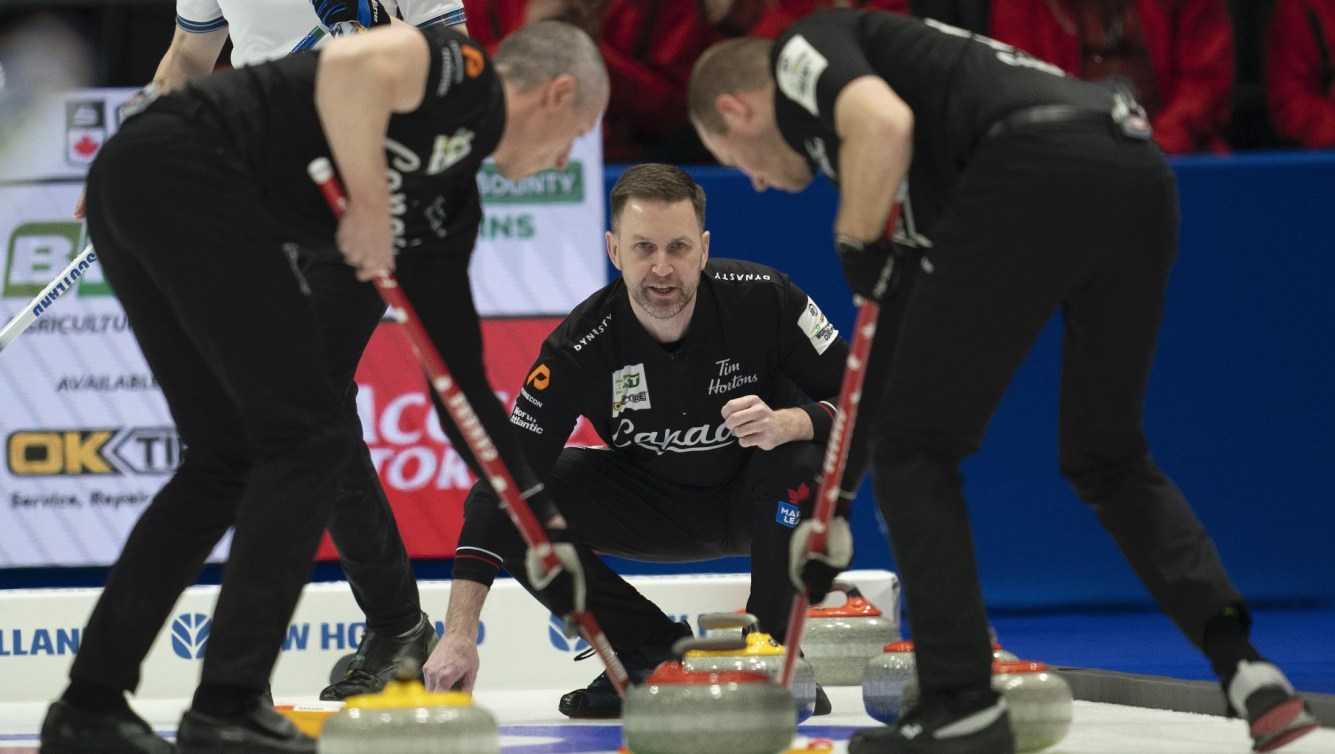 Canada skip Brad Gushue watches a shot approach the house as second EJ Harnden (left) and lead Geoff Walker sweep during second end action against Scotland in finals at the Men's World Curling Championship, in Ottawa, Sunday, April 9, 2023. THE CANADIAN PRESS/Adrian Wyld