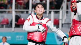 A taekwondo athlete in red vest smiles