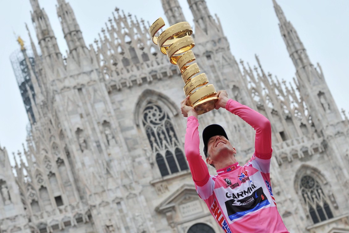 Ryder Hesjedal tiene sopra la sua testa il trofeo del Giro d'Italia davanti a una grande cattedrale