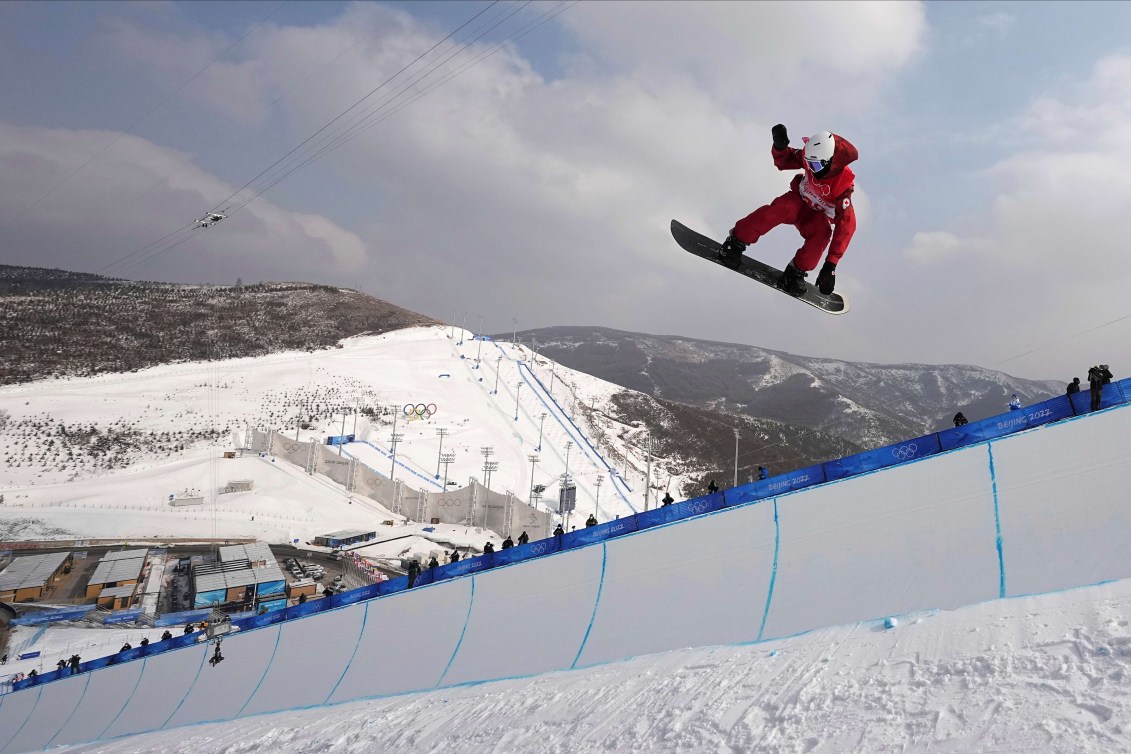 Liam Gill grabs his board as he performs a trick in a halfpipe