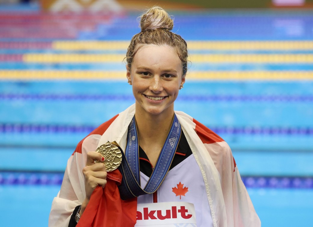 Summer McIntosh poses with her gold medal and a Canadian flag draped over her shoulder