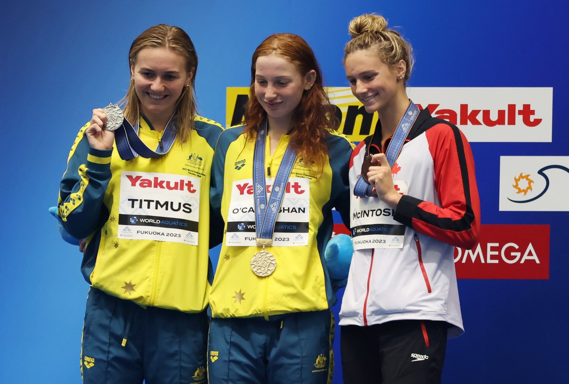 Summer McIntosh and two Australian swimmers show of their medals on the podium