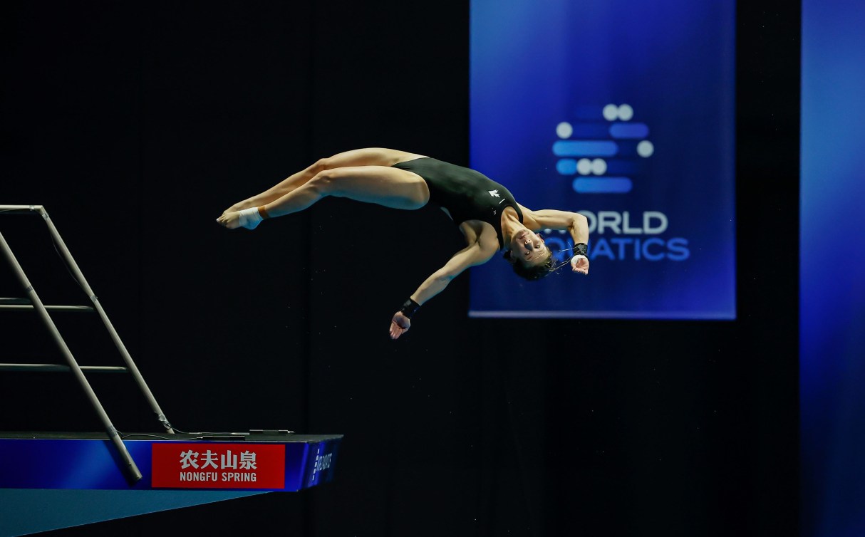 Caeli McKay dives off the 10m platform in front of world championship banner