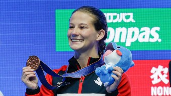 Caeli McKay holds up her bronze medal on the podium at the World Aquatics Championships
