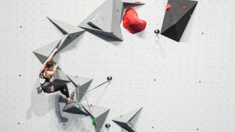 A sport climber navigates a series of gray triangular holds
