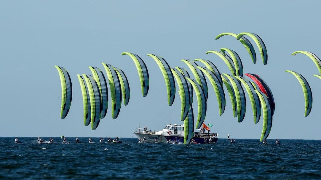 Numerous kite surfers grouped together on a start line