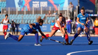 Two field hockey players battle for the ball