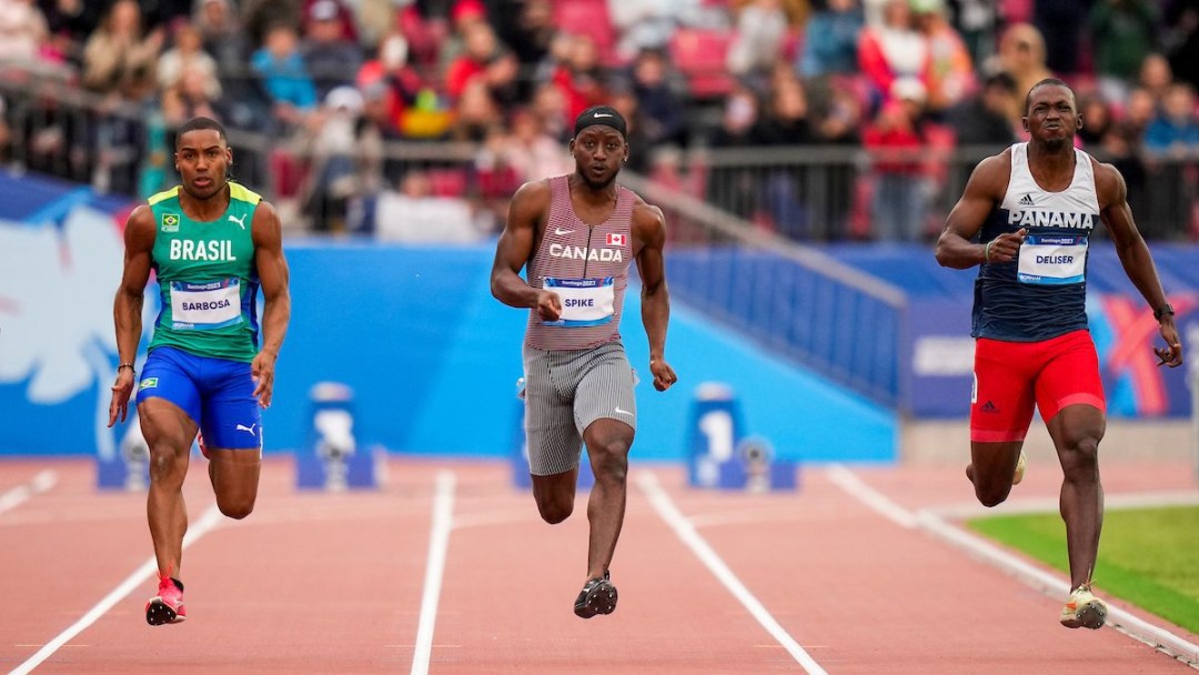 Three athletes sprint on the track, Norris Spike is in the middle in a Team Canada uniform