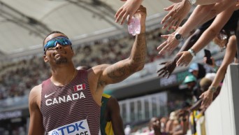 Andre De Grasse, of Canada, receives high fives from fans during the men's 200-meter heat at the World Athletics Championships in Budapest, Hungary, Wednesday, Aug. 23, 2023. (AP Photo/Ashley Landis)