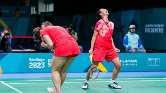 Two female badminton players in red scream in happy reaction
