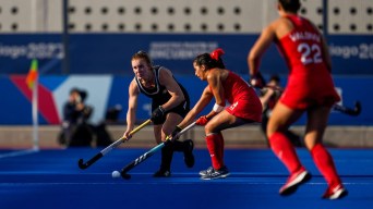 Three field hockey players battle for the ball