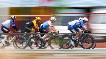 Five road cyclists race past a blurry background