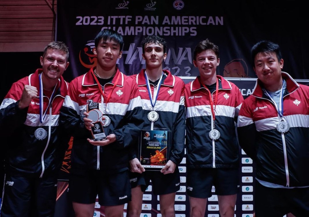 Five Canadian table tennis players wear silver medals on a podium 