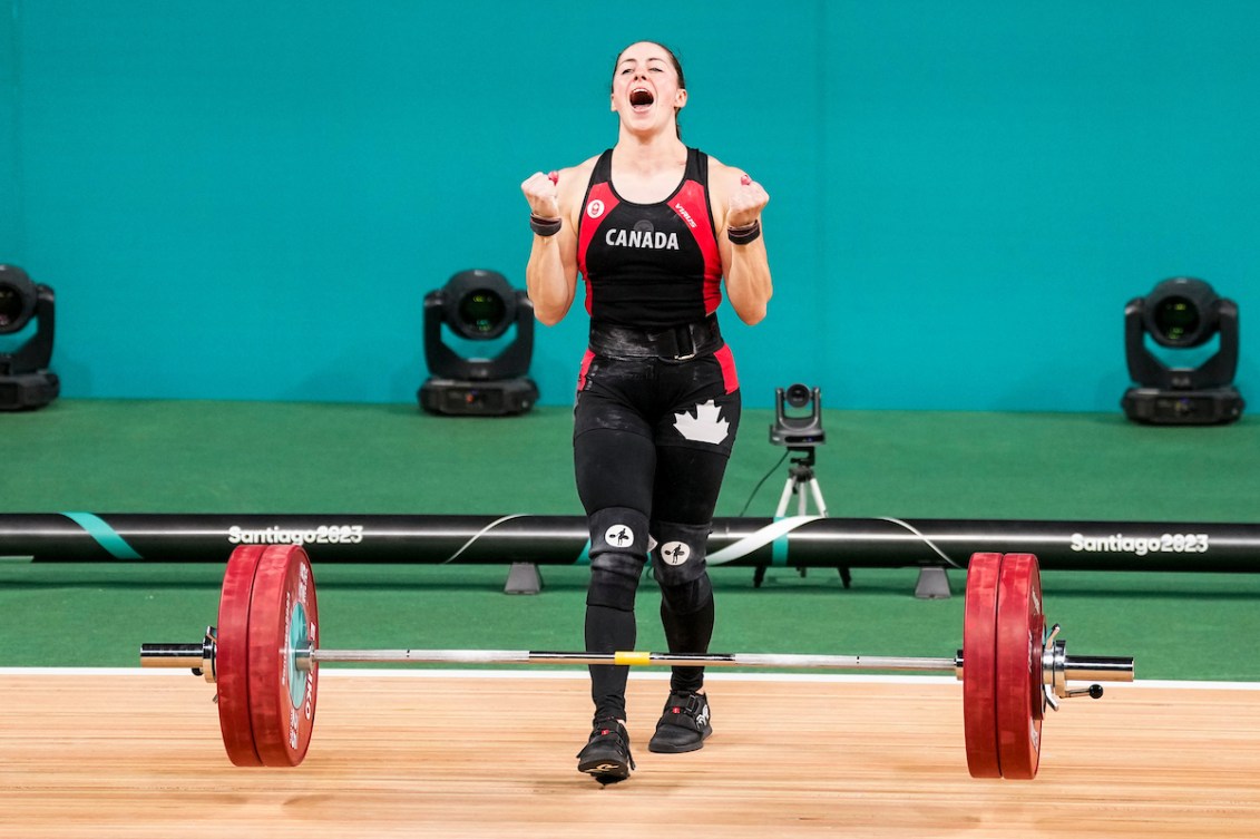 Maude Charron pumps her fists and yells after dropping the weight from a successful lift 