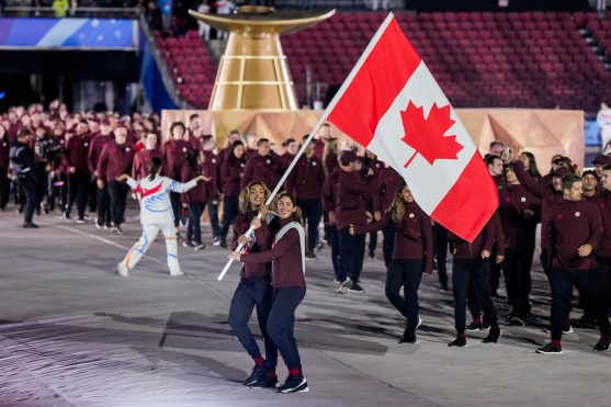 Brandie Wilkerson and Melissa Humana-Paredes carry the Canadian flag in front of their teammates