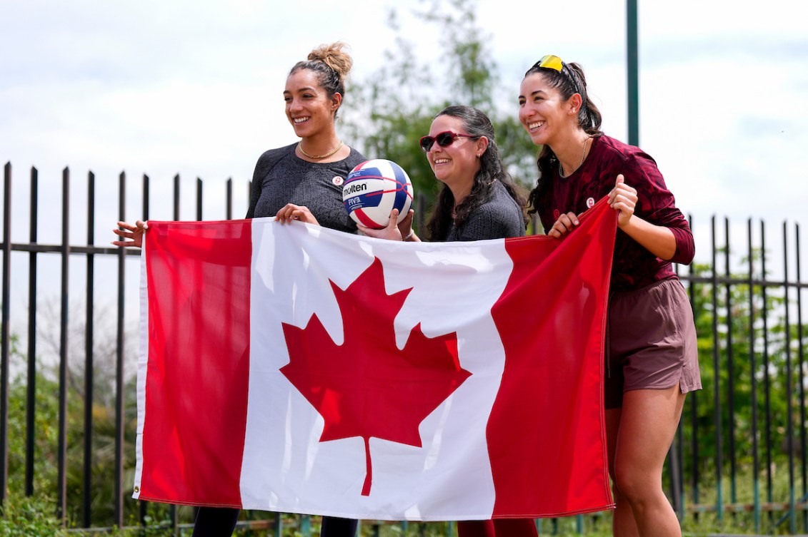 Melissa Humana-Paredes and Brandie Wilkerson pose with Chef de Mission Christine Girard and the Canadian flag 