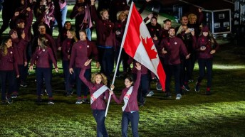 Brandie Wilkerson and Melissa Humana-Paredes carry the Canadian flag in front of their teammates