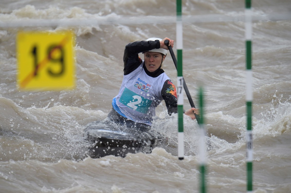 A slalom canoer paddles towards green and white striped gates
