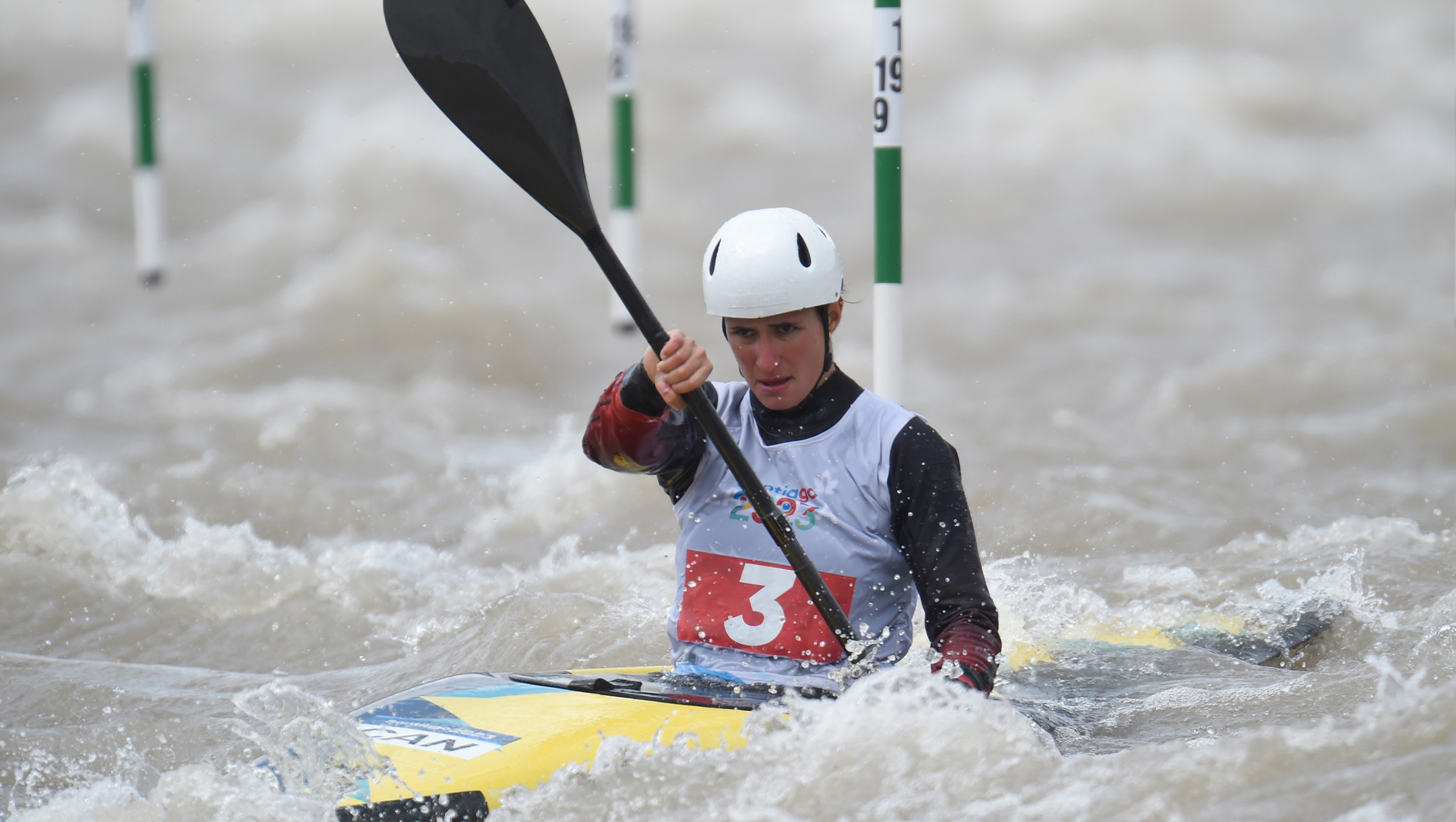 Lea Baldoni paddles her kayak past green and white striped gates
