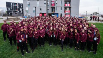 Many members of Team Canada pose outside their building in the Athlete Village