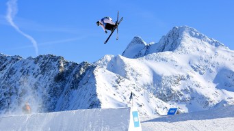 A freestyle skier crosses his skis in a jump over a snow ramp