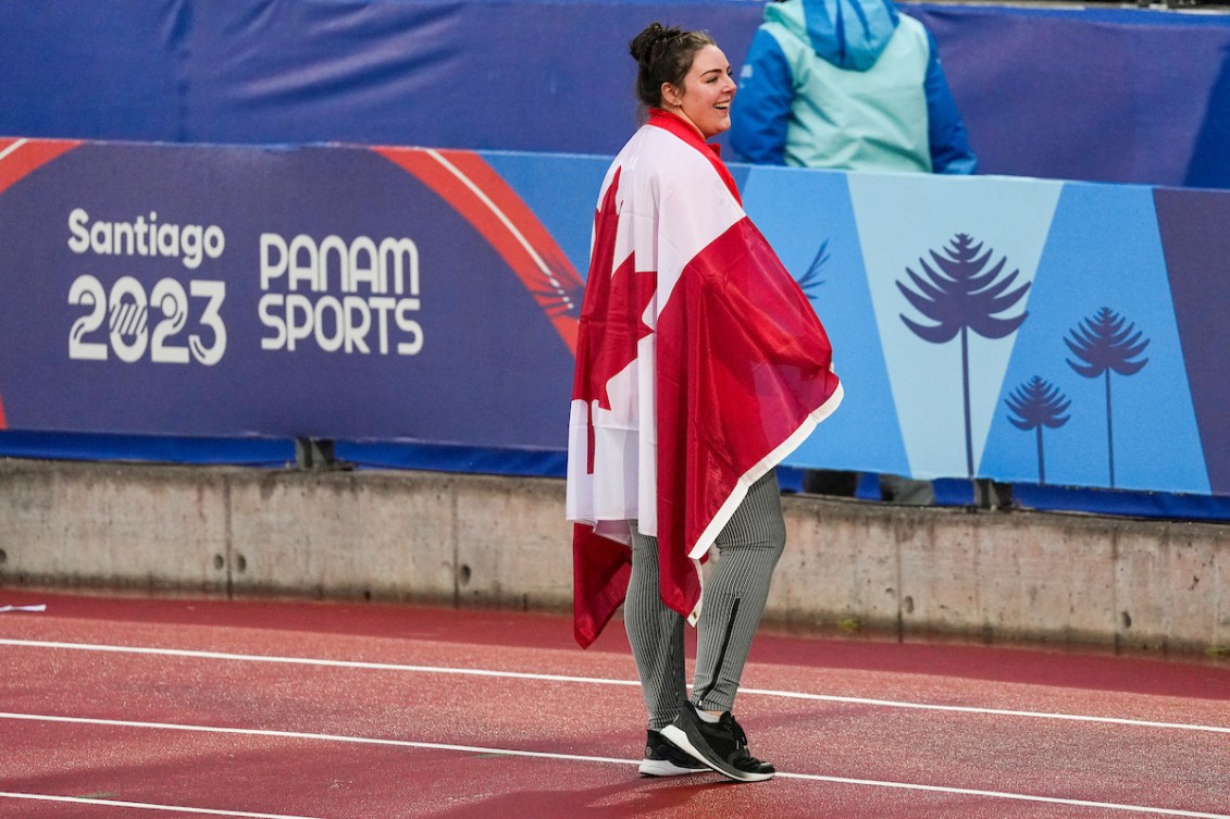 Kaila Butler stands on the track draped in a Canadian flag