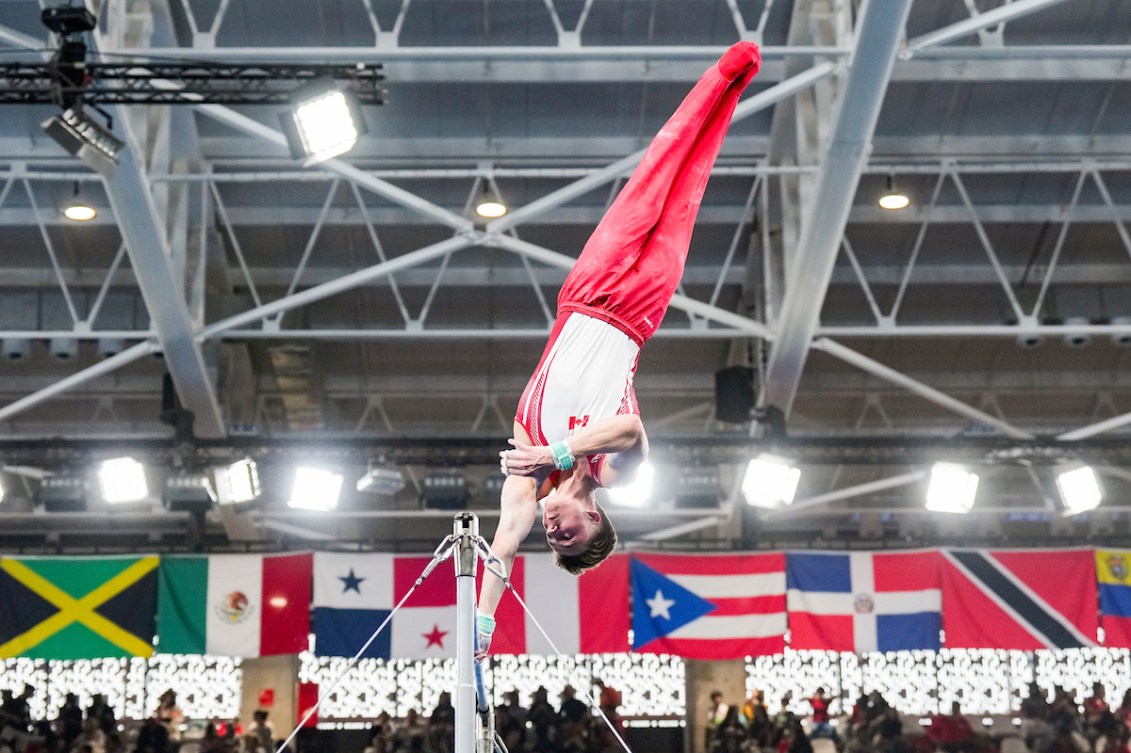 Felix Dolci does a one handed swing on the horizontal bar