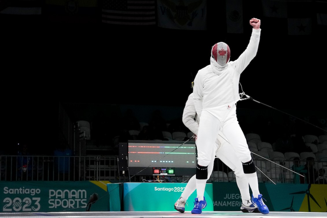 Canadian fencer Fares Arfa pumps his fist in celebration while wearing a Canadian face shield