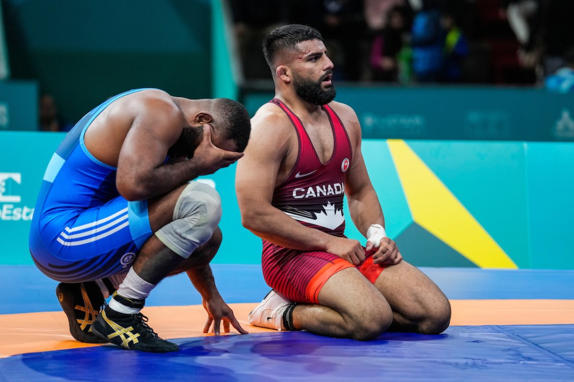 One wrestler crouches with his head in his hands while the other kneels
