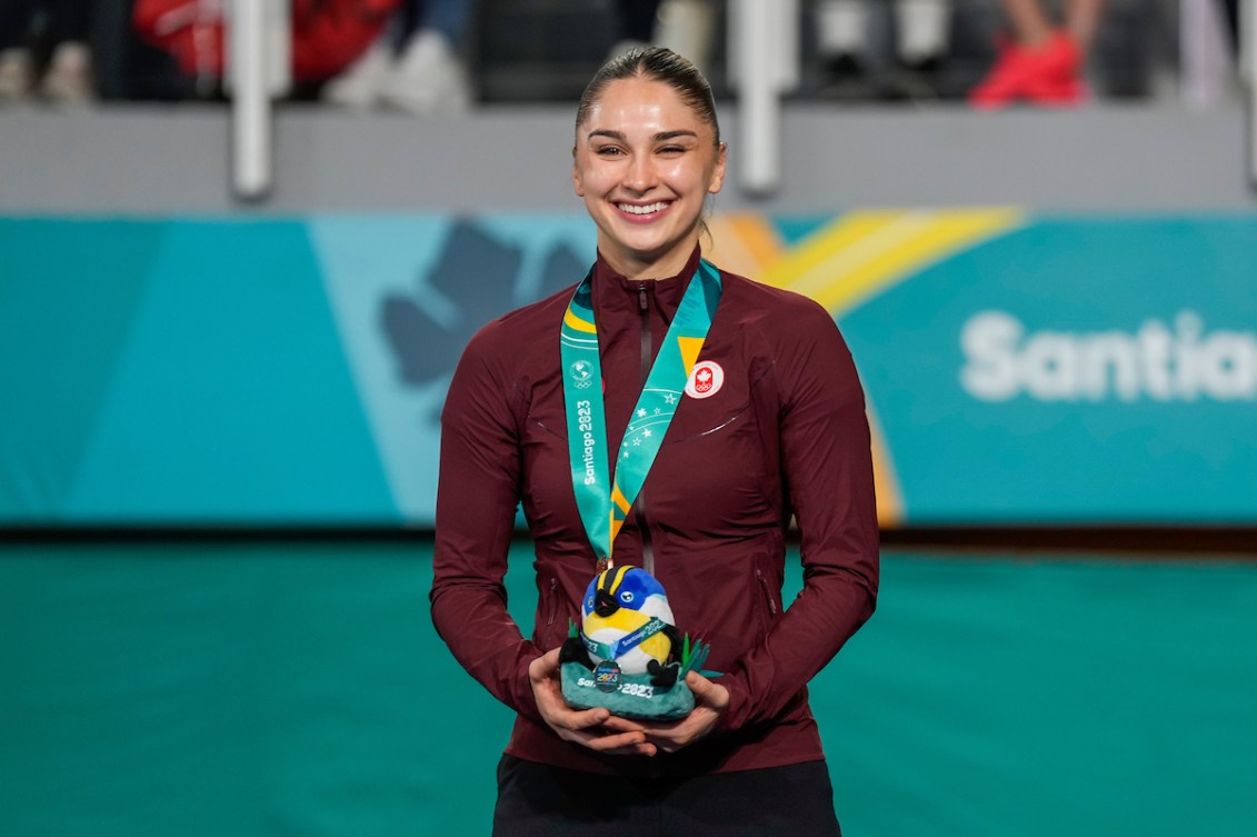 A Team Canada athlete stands on the podium with a silver medal.