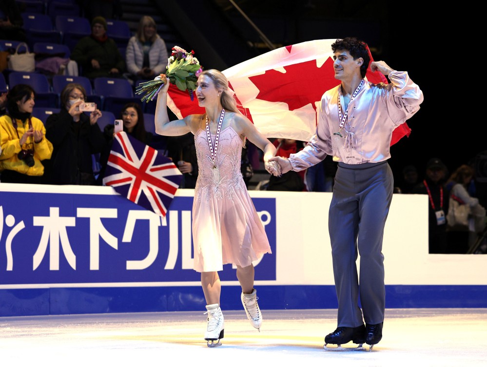 Piper Gilles and Paul Poirier do a victory lap with the Canadian flag