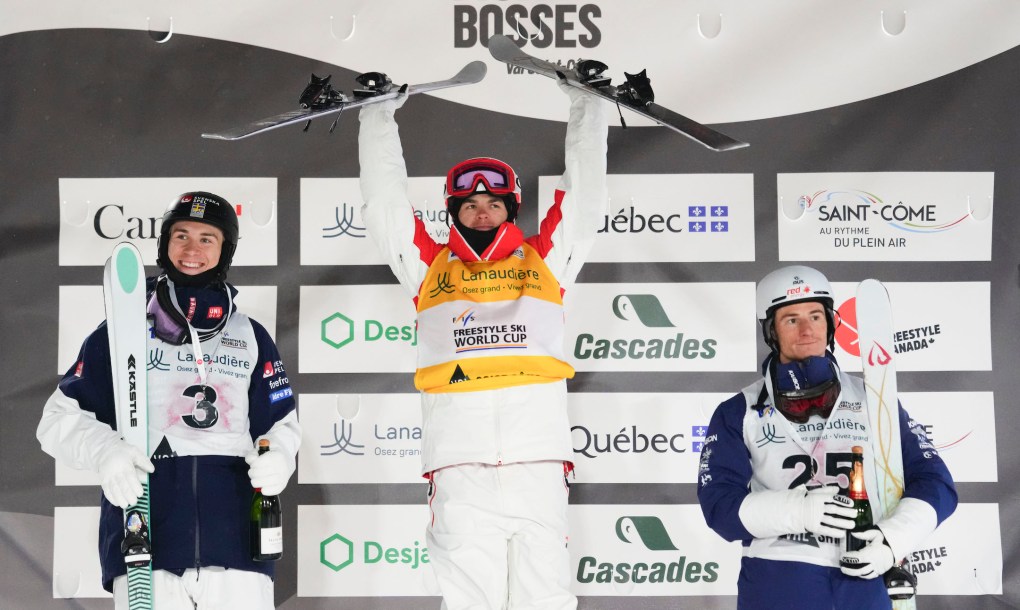 Canada's Mikael Kingsbury celebrates gold as he stands on the podium with Sweden's Filip Gravenfors, left, who took silver and bronze medalist Australia's Matt Graham in the freestyle ski world cup men's dual moguls at Val Saint-Come, Que., on Saturday, Jan. 20, 2024. THE CANADIAN PRESS/Sean Kilpatrick