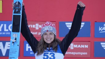 Abigail Strate lifts her hands in victory while holding her skis.