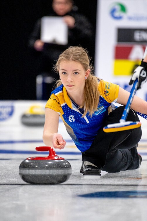 Curling athlete slides on the ice as she prepares to throw a stone