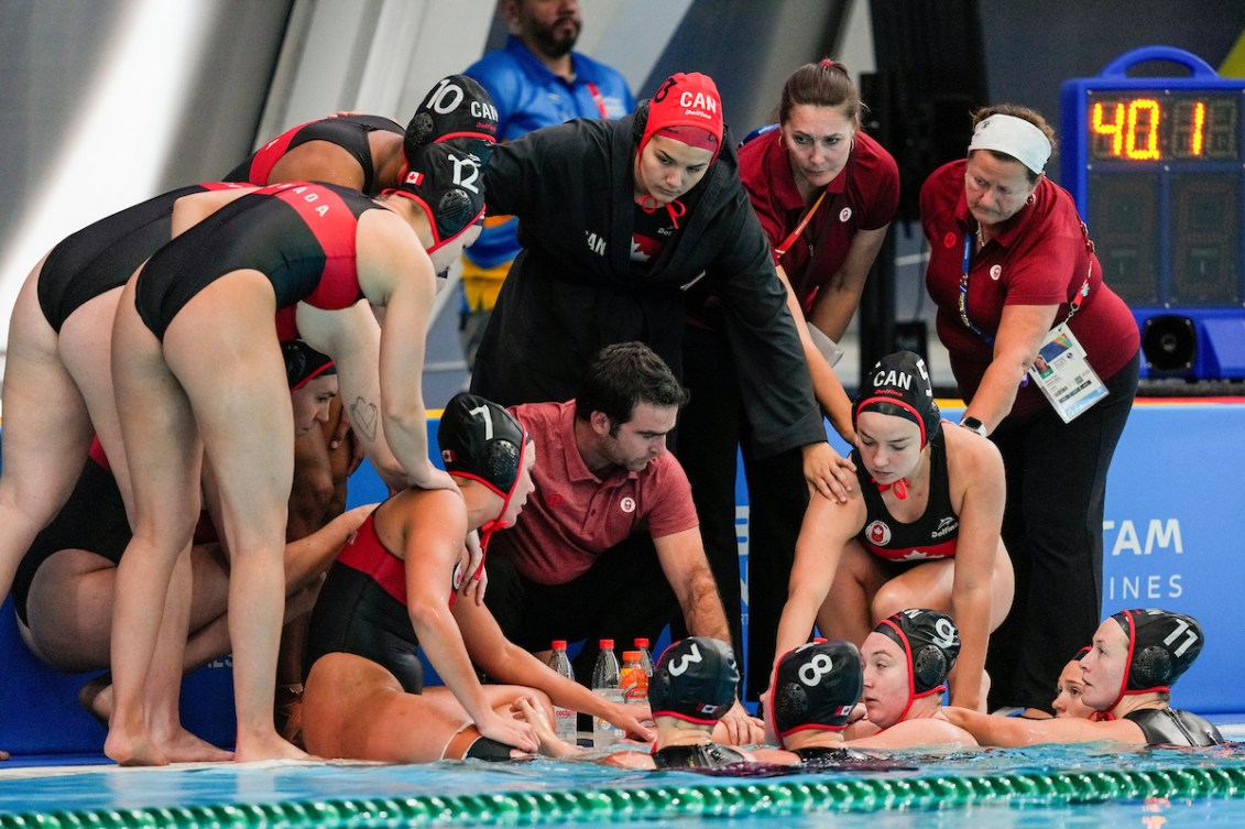 Team Canada's women's water polo team has a huddle at the side of the pool